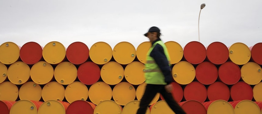 Hombre caminando cerca de barriles de lubricantes