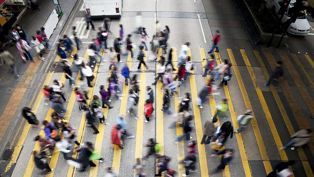 Personas cruzando una calle llena de gente en Hong Kong