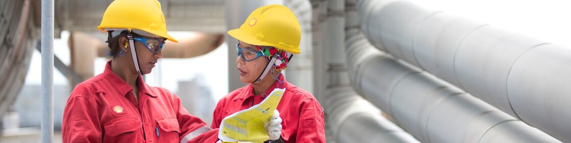 dos trabajadores hablando sobre un proyecto en una refinería en Malasia