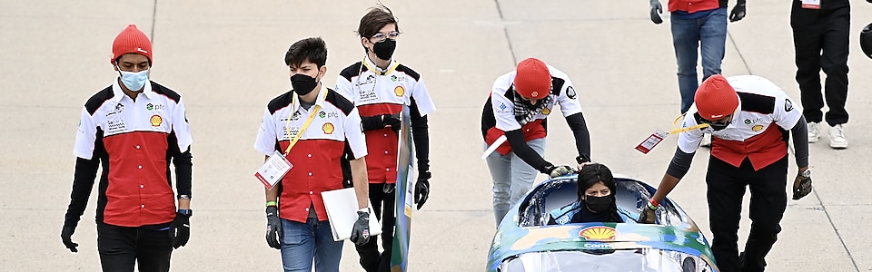 Integrantes de la escudería Borregos CCM del Tec CCM caminando al lado de su prototipo hacia la pista en Indy 500