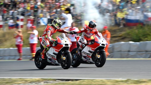 Two bikers shaking hands as they ride