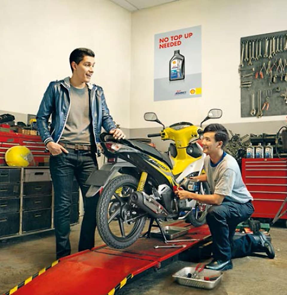 dos motociclistas cambiando el aceite de una motocicleta