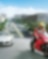 Motocicleta roja y piloto en una ruta con autos y edificios en el fondo