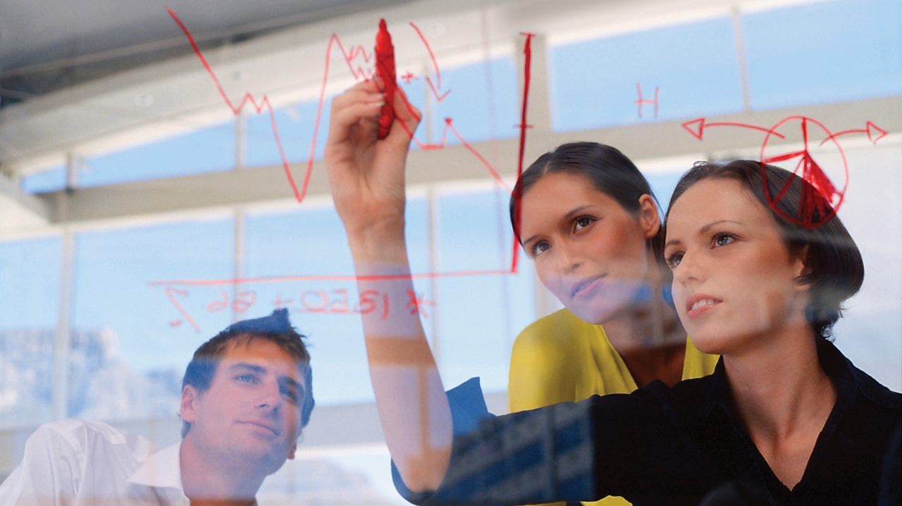 Mujer de negocios dibujando gráficos en una pizarra transparente