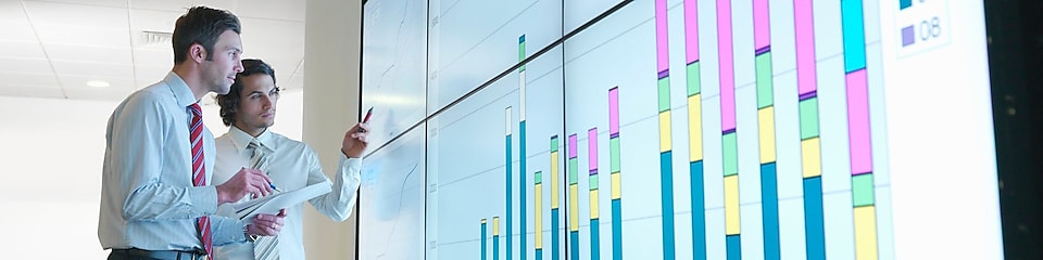 Hombres de negocios analizan informes visualizados en una gran pantalla digital