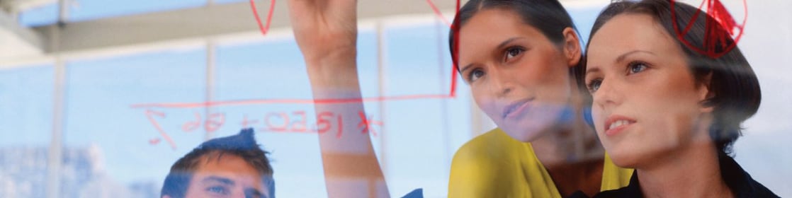 Mujer de negocios dibujando gráficos en una pizarra transparente